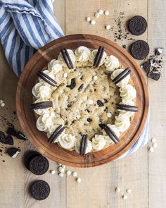 an oreo cookie cake with white frosting and cookies around it on a wooden platter