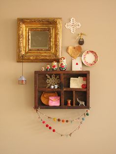 a wooden shelf with many items on it and a gold framed mirror hanging above it