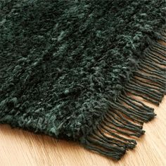 a green rug with fringes is laying on the floor