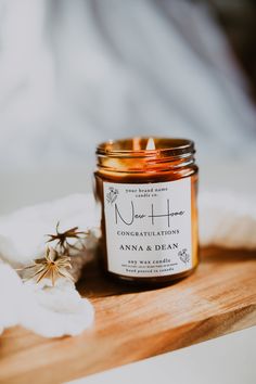 a candle sitting on top of a wooden table next to a white flower and napkin