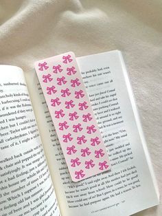 a bookmark with pink bows on it laying next to an open page of a book