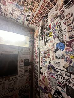 a wall covered in pictures and stickers next to a window with light coming through