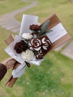 a bouquet of flowers is being held by someone's hand on the grass outside