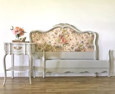 a white bed sitting next to a table with flowers on it