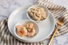 two small white bowls filled with food on top of a plate next to a fork