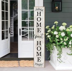 a wooden sign that says home sweet home next to a potted plant and door