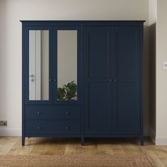 a large blue armoire in a room with hardwood floors and white walls, along with a rug on the floor