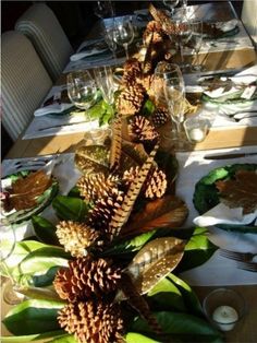 the table is set with pine cones and greenery