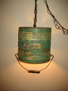 a green bucket hanging from a chain on a wall with a light in the middle