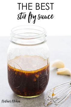 the best stir fry sauce in a mason jar with whisk and spoons next to it