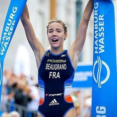 a woman is holding up her arms in the air while wearing a blue swimsuit