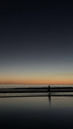 a person walking on the beach at sunset