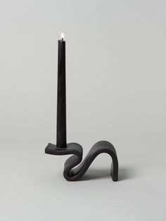 a black candle holder sitting on top of a white floor next to a gray wall