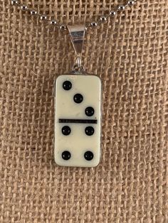 a white and black square shaped pendant on a silver plated chain with beads hanging from it's end