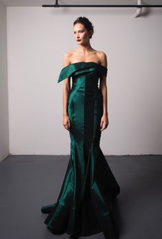 a woman in a long green dress posing for the camera with her hands on her hips