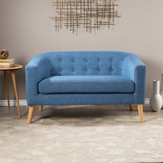 a blue couch sitting next to a wooden table with a vase on top of it