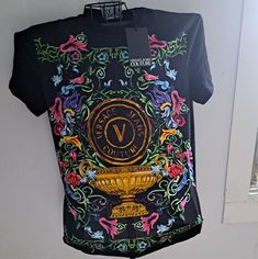 Versace’s Cotton T-Shirt Features A Large V Emblem Framed By A Vibrant Floral Motif. Round Neck Short Sleeves Straight Hem Pulls Over 100% Cotton Machine Wash Made In Italy Size & Fit About 28” From Shoulder To Hem Model Measurements: 6’2” Tall Model Is Wearing A Us Size Medium Luxury Spring Graphic Print Shirt, Designer Multicolor Graphic Print Tops, Designer Fitted T-shirt With Graphic Print, Luxury Graphic Print Tops For Summer, Designer Fitted Short Sleeve T-shirt, Designer Fitted T-shirt For Spring, Luxury Crew Neck Tops For Spring, Luxury Fitted T-shirt For Summer, Designer Graphic Print T-shirt For Spring