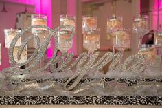 there are many glasses on the table with name spelled out in them and some candles