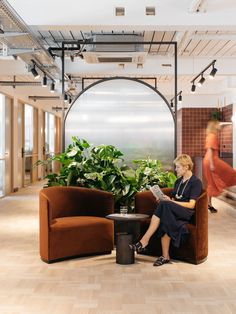 a woman sitting on a chair in an office with potted plants next to her