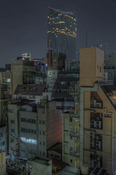 the city skyline is lit up at night, with skyscrapers in the foreground