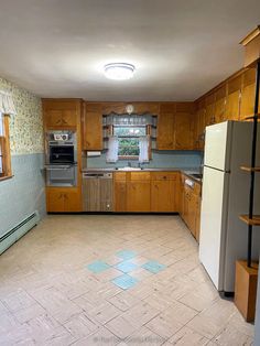 an empty kitchen with tile flooring and wooden cabinets, including refrigerator freezer oven and dishwasher