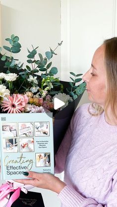 a woman is holding a box with flowers in it and she is looking at the book