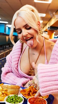 a woman sticking her tongue out while eating food at a table with other plates and bowls