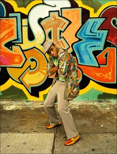 a man standing in front of a graffiti covered wall