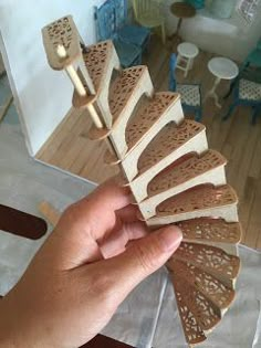 a hand holding a piece of wood that is shaped like a fan