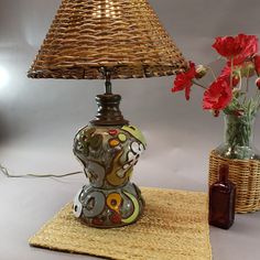 a table lamp sitting on top of a rug next to a vase with flowers in it