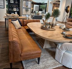 a living room filled with furniture and a large wooden table surrounded by white couches