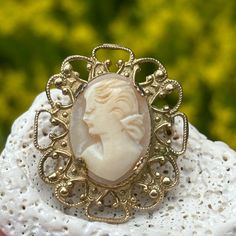 Vintage carved cameo brooch on a gold tone metal prong set setting. This is a small cameo measuring approximately 1 and 1/4" from top to bottom and 1" across. The pin and latch are in good working order. The cameo feels secure in the prong settings. This is unsigned but a lovely carved left facing cameo! Please see all photos and if have any additional questions please message me! Thank you for looking! Ornate Carved Gold Brooches, Ornate Gold Carved Brooches, Vintage Gold Carved Brooches, Gold Oval Cameo Brooch, Carved Gold Brooch For Gift, Carved Gold Brooches As Gifts, Carved Gold Brooches For Gift, Ornate Cameo Brooch For Anniversary, Ornate Cameo Brooches For Anniversary