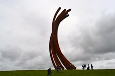 several people are standing in front of a large sculpture on the top of a hill