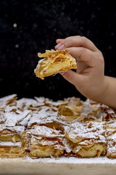 a person is holding up a piece of food with powdered sugar on it,