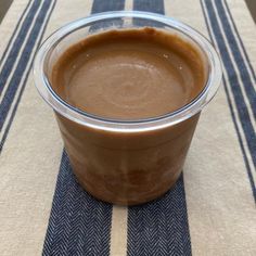 a plastic cup filled with brown liquid on top of a blue and white table cloth