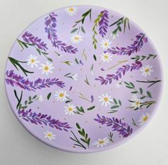 a purple plate with white and yellow flowers painted on the side, sitting on a table