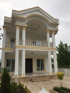 a large white and yellow house with columns on the front, stairs up to the second floor