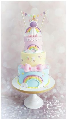 a three tiered cake is decorated with rainbows and unicorns on the top