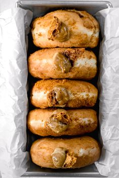 four doughnuts in a tin lined with wax paper