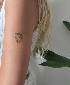 a woman's arm with a small tattoo of a strawberry on the left side