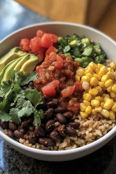 a white bowl filled with rice, beans, avocado and other veggies