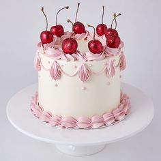 a white cake with pink icing and cherries on top