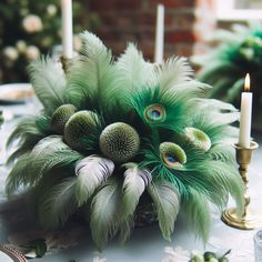 a table topped with lots of green feathers next to a lit candle on top of a table