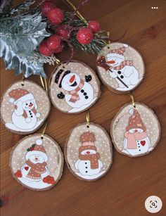 christmas ornaments with snowmen on them sitting on a wooden table next to a tree