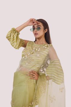 The stylish green organza saree with cold-shoulder balloon-sleeved blouse, embroidered with cut dana, off-white stripes blouse. Shop designer saris online in the USA from Pure Elegance. Disclaimer: The actual product may vary slightly from the image. These are custom orders, hence expect slight variation in color and placement of the motif or buta. ESTIMATED DELIVERYBecause this is a custom order, it would take about 4 weeks from the date of purchase. RETURN POLICYThis product is a custom order and cannot be returned or exchanged. Green Organza Saree, Stripes Blouse, Suits Indian, Sharara Suits, Pure Elegance, Fashion Journals, Balloon Sleeve Blouse, Traditional Fabric, Organza Saree