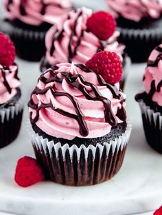 cupcakes with raspberries and chocolate frosting on a white plate, ready to be eaten