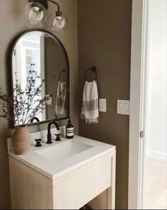 a white sink sitting under a bathroom mirror next to a wall mounted faucet