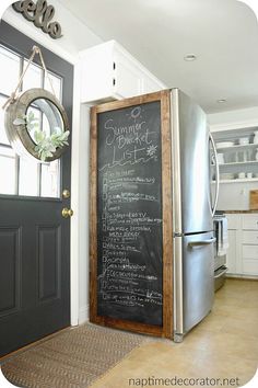 a chalkboard with writing on it is in front of a black door and white cabinets