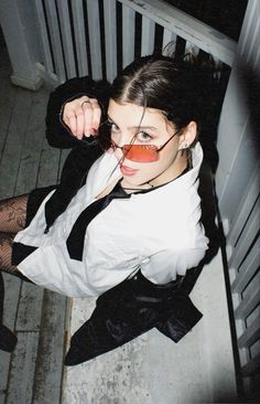 a woman in black and white outfit holding onto her face with an orange nose ring