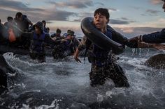 a group of people in the water with life vests on and one person holding a raft